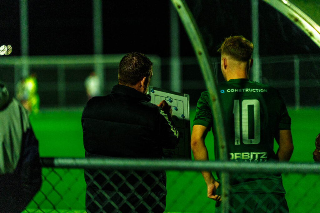 A football coach briefs a player using a whiteboard before entering the football match.