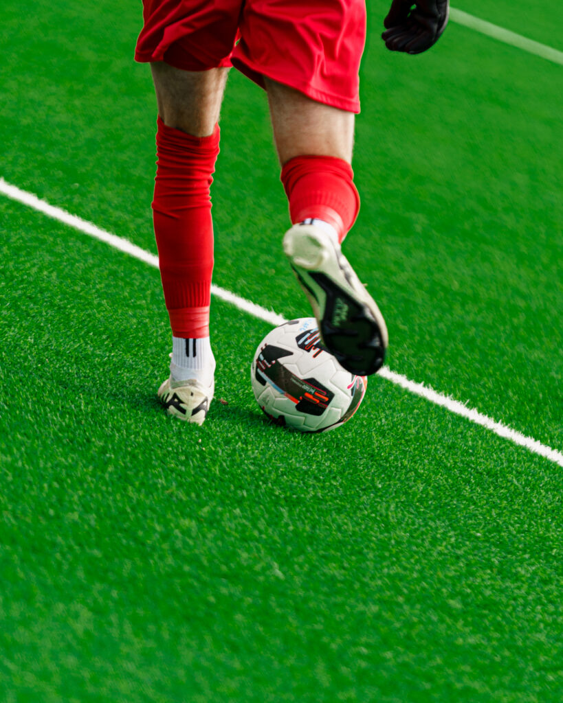 A close up image of the Auckland United FC goalkeeper dribbling the ball.