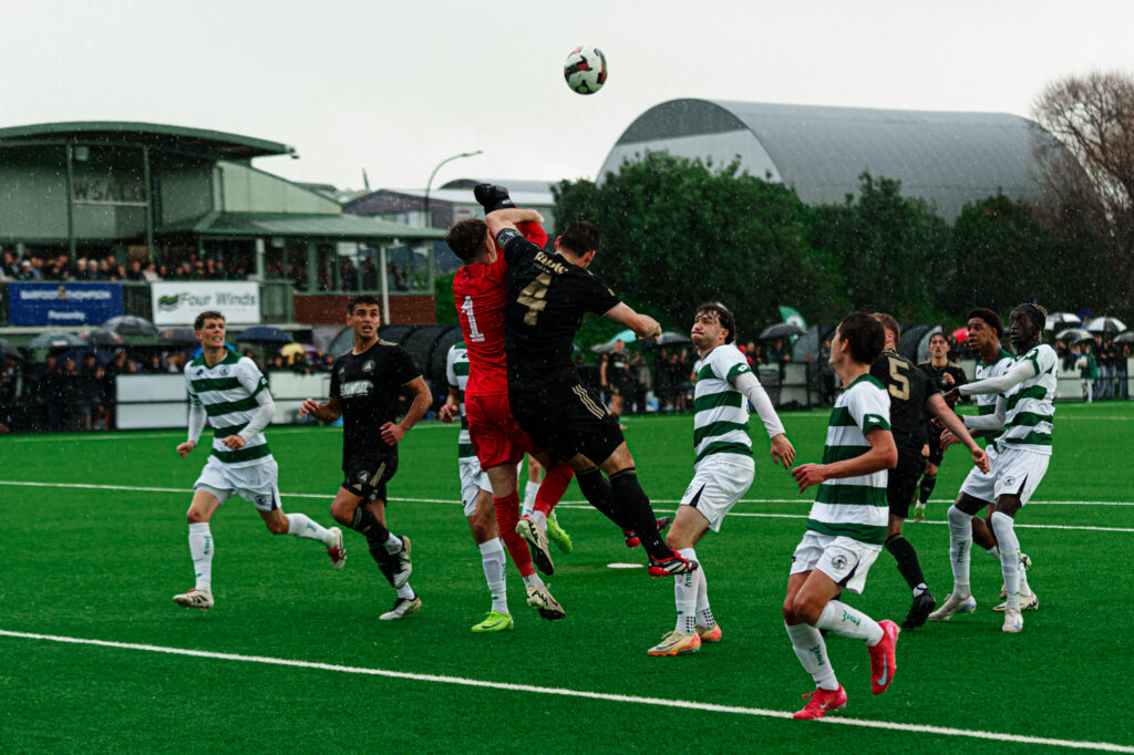 Two football player leap into the air to intercept a football during a match.